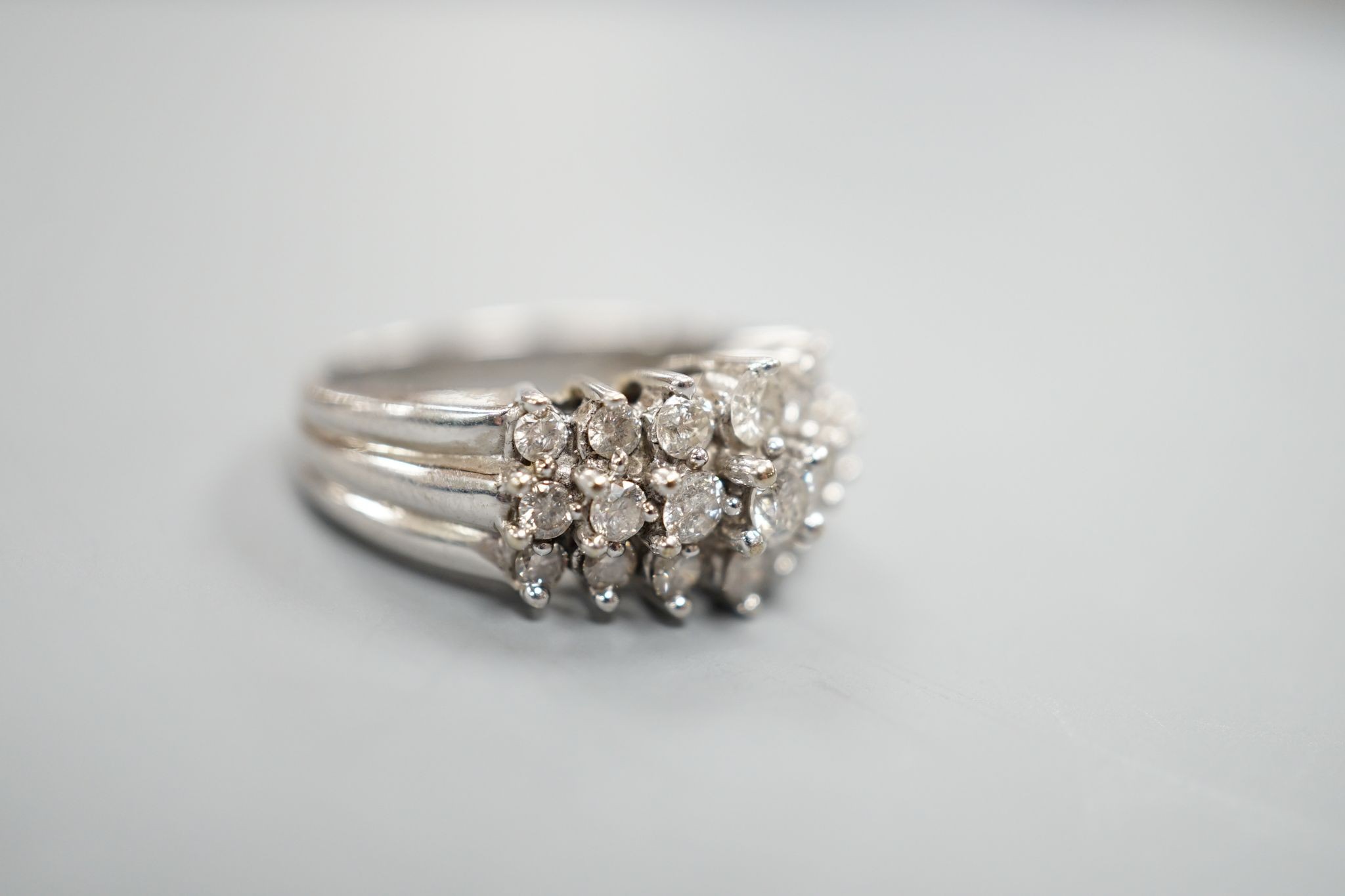 A modern 10k white metal and three row graduated diamond cluster set dress ring, size L, gross weight 4.3 grams.